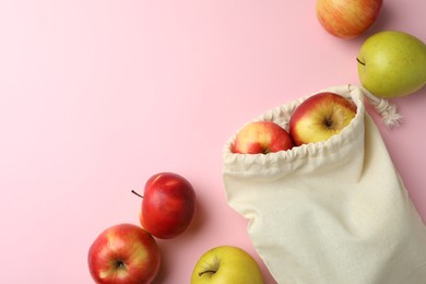 Photo of Cotton eco bag and apples on pink background, flat lay. Space for text