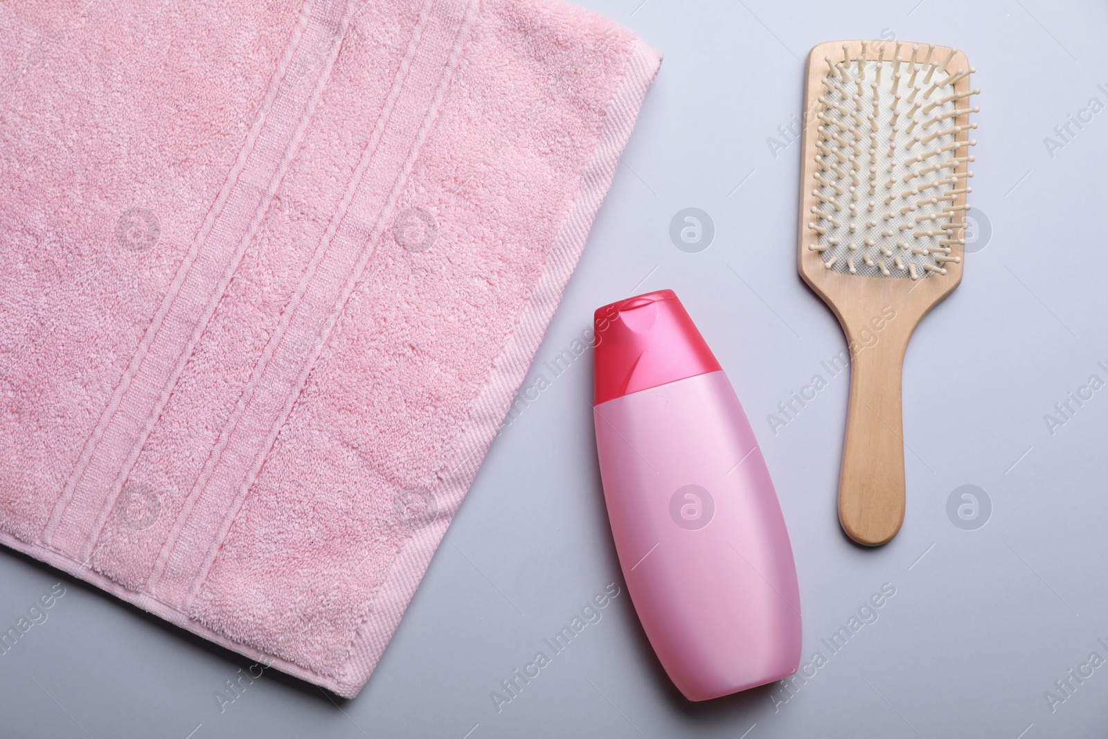 Photo of Bottle with shampoo, towel and brush on color background, flat lay