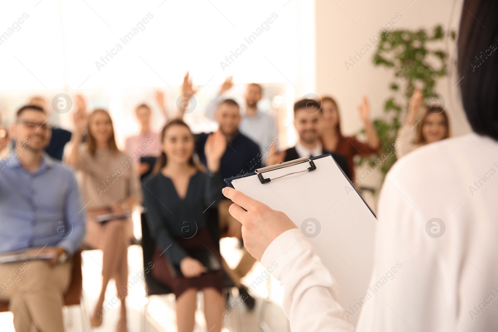 Photo of Business trainer with clipboard answering questions indoors, closeup