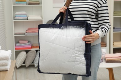 Woman holding bag with duvet in home textiles store, closeup. Space for text