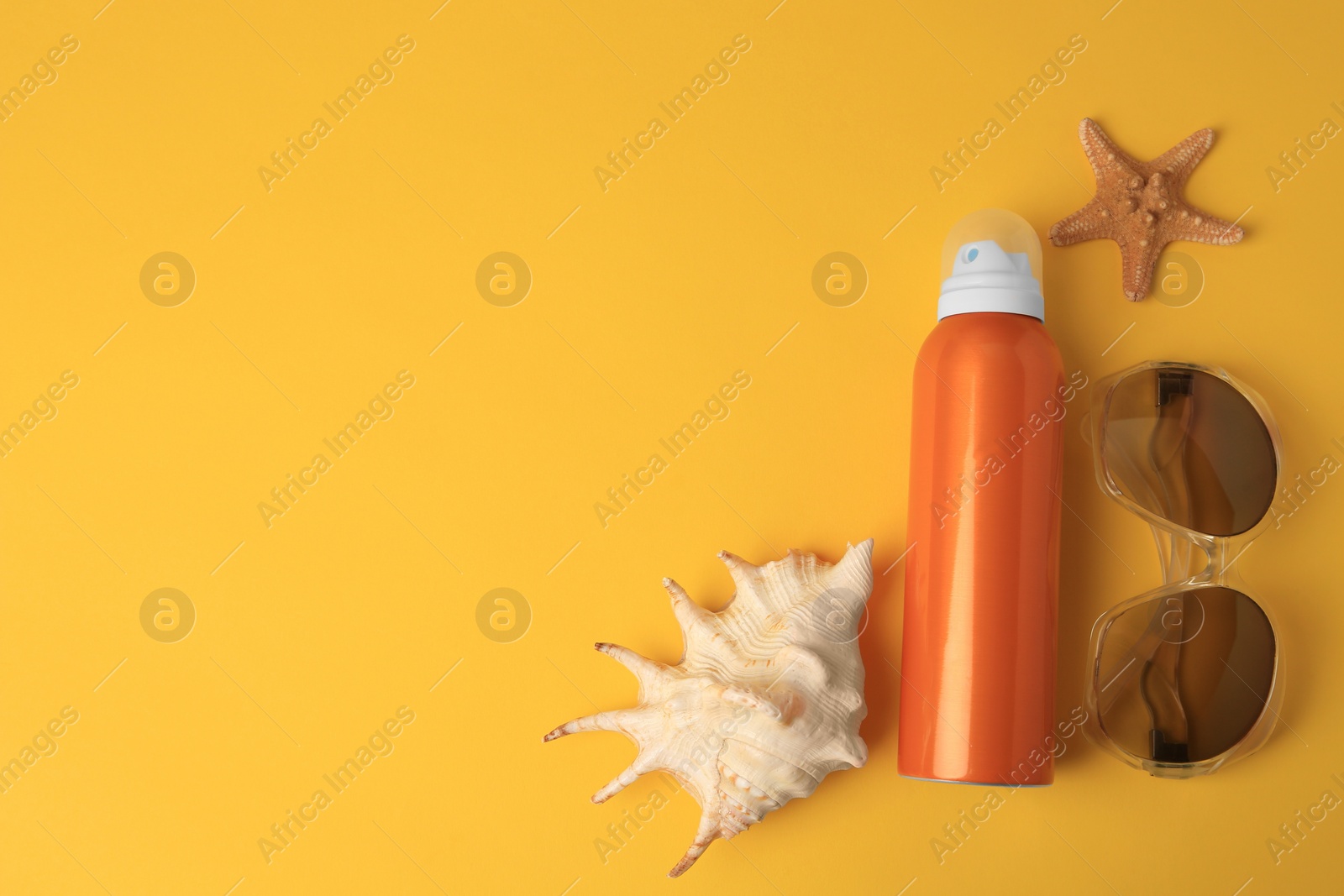 Photo of Bottle of sunscreen, starfish, seashell and sunglasses on yellow background, flat lay. Space for text