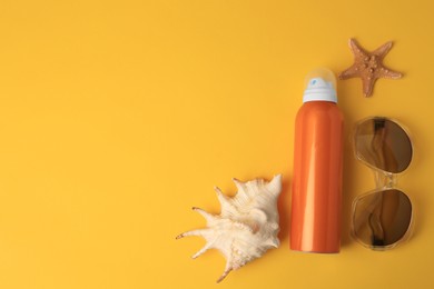 Bottle of sunscreen, starfish, seashell and sunglasses on yellow background, flat lay. Space for text