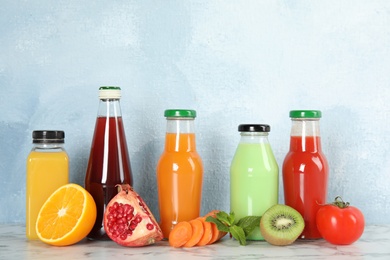 Photo of Bottles with different drinks and ingredients on table against color background