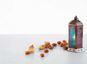 Photo of Muslim lamp and dates on table against white background. Space for text