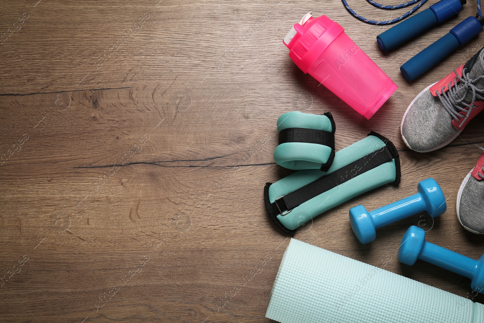 Photo of Turquoise weighting agents and sport equipment on wooden table, flat lay. Space for text