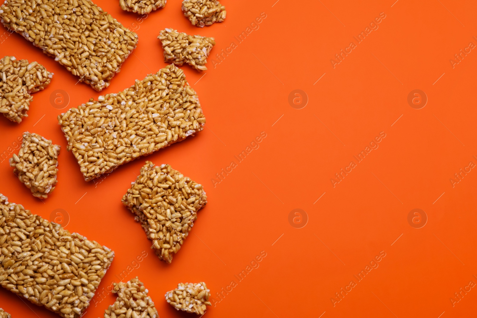 Photo of Puffed rice bars (kozinaki) on orange background, flat lay. Space for text