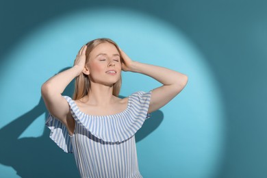 Photo of Beautiful young woman in sunlight on light blue background, space for text