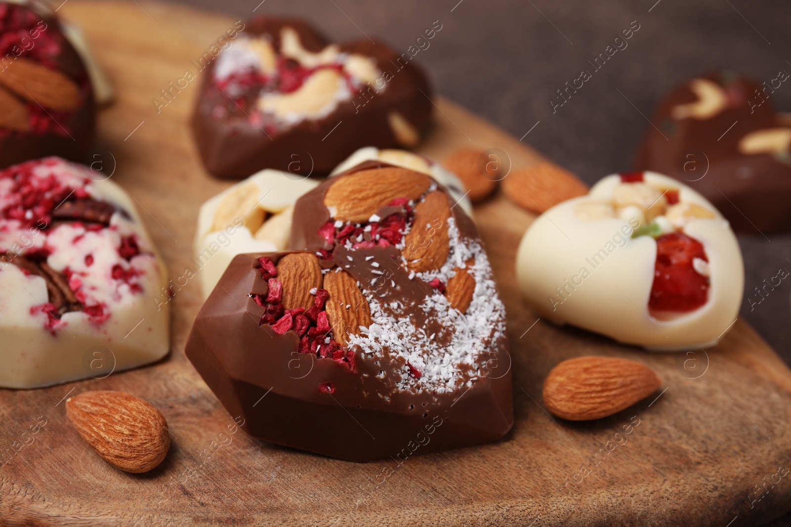 Photo of Tasty chocolate heart shaped candies with nuts, closeup