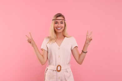 Photo of Portraitsmiling hippie woman showing peace signs on pink background