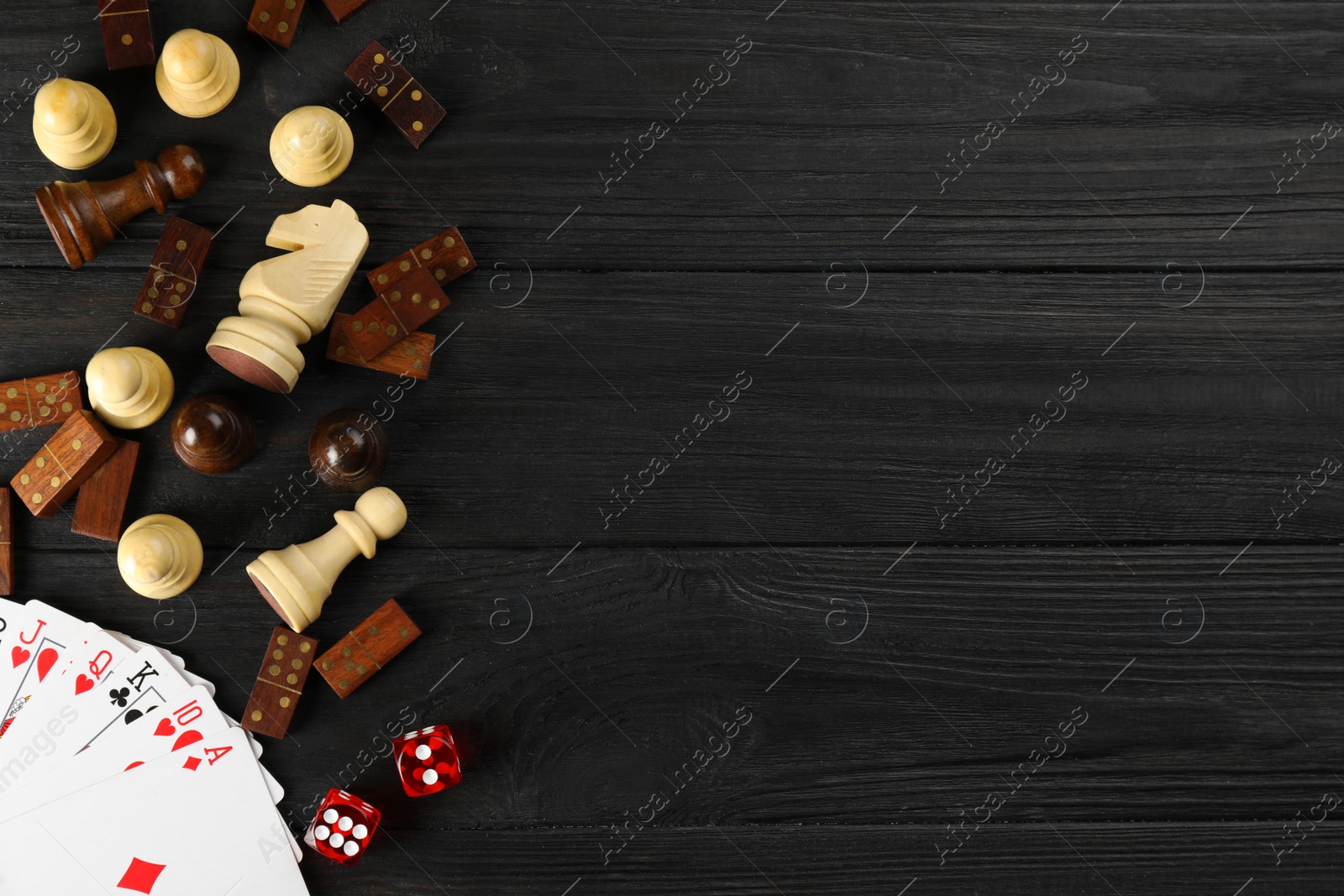 Photo of Elements of different board games on dark wooden table, flat lay. Space for text