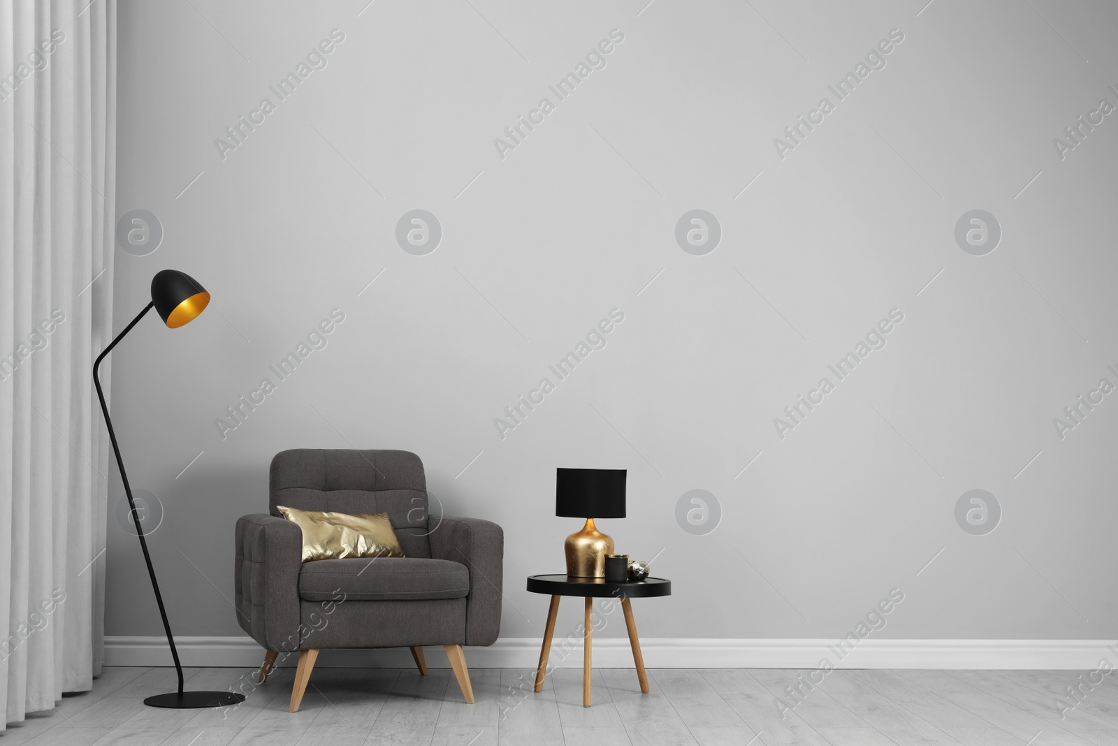 Photo of Stylish interior with armchair, table and floor lamp near wall in room, space for text
