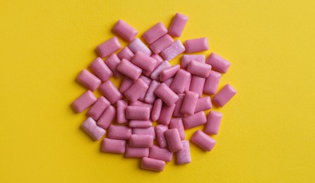 Photo of Sweet chewing gums on yellow background, flat lay