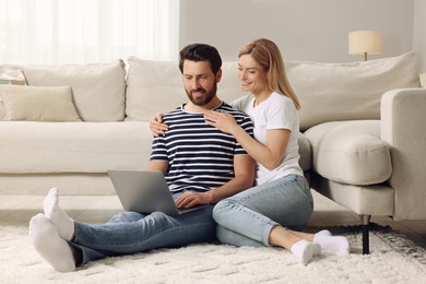 Photo of Happy couple with laptop on floor at home