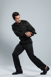 Male security guard in uniform with gun on grey background