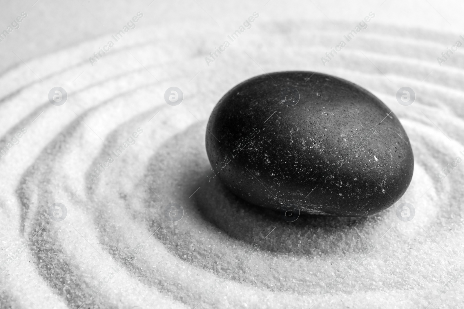 Photo of Black stone on sand with pattern. Zen, meditation, harmony