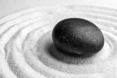 Black stone on sand with pattern. Zen, meditation, harmony