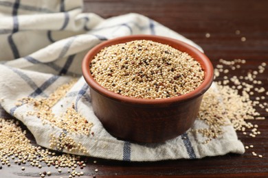Photo of Bowl with raw quinoa seeds on wooden table, closeup