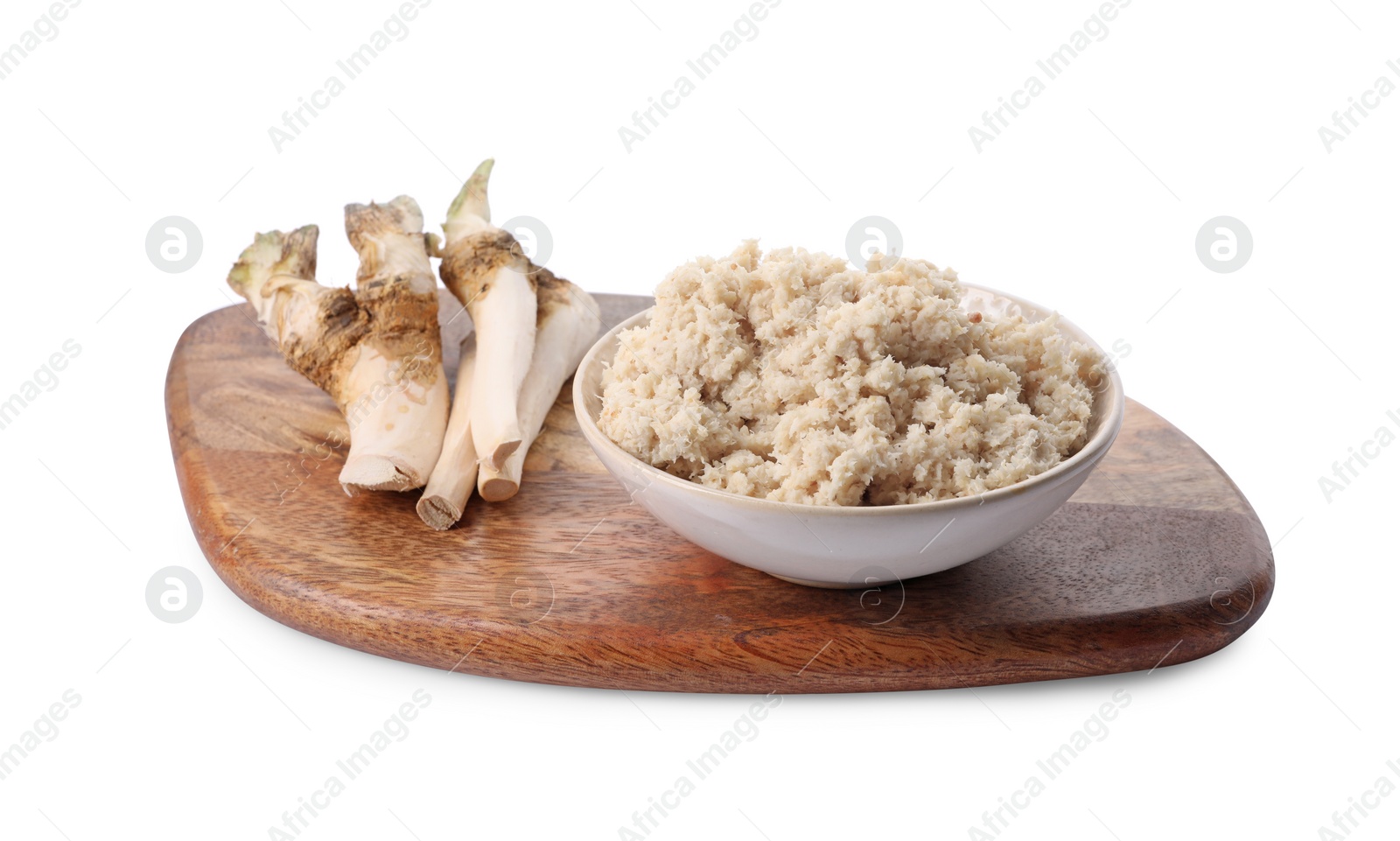 Photo of Wooden board with bowl of tasty prepared horseradish and roots isolated on white