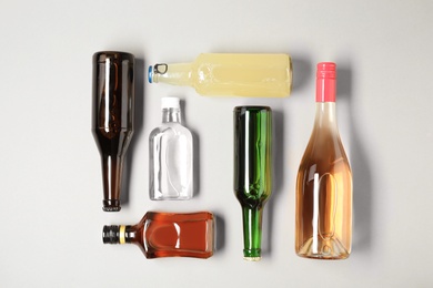 Photo of Bottles with different alcoholic drinks on light background, top view