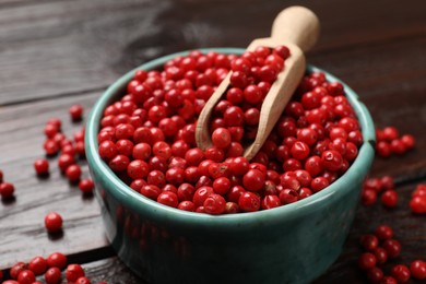 Photo of Aromatic spice. Red pepper in bowl and scoop on wooden table, closeup