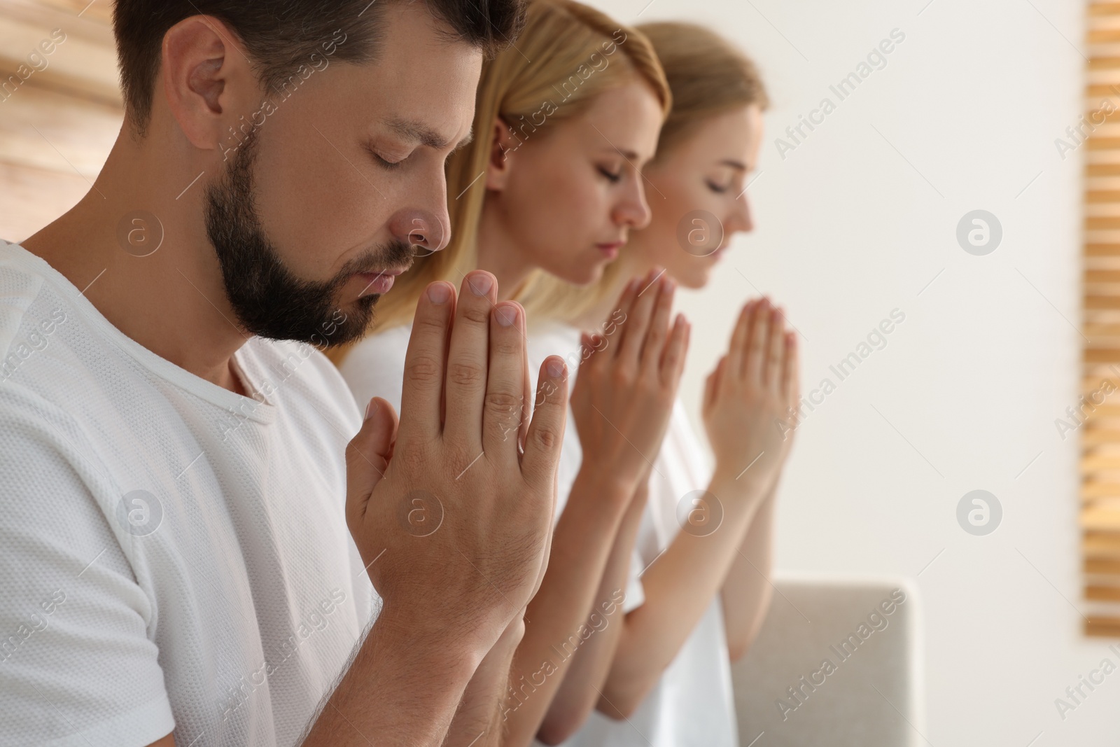 Photo of Group of religious people praying together indoors. Space for text