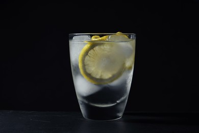 Shot of vodka with lemon and ice on black table