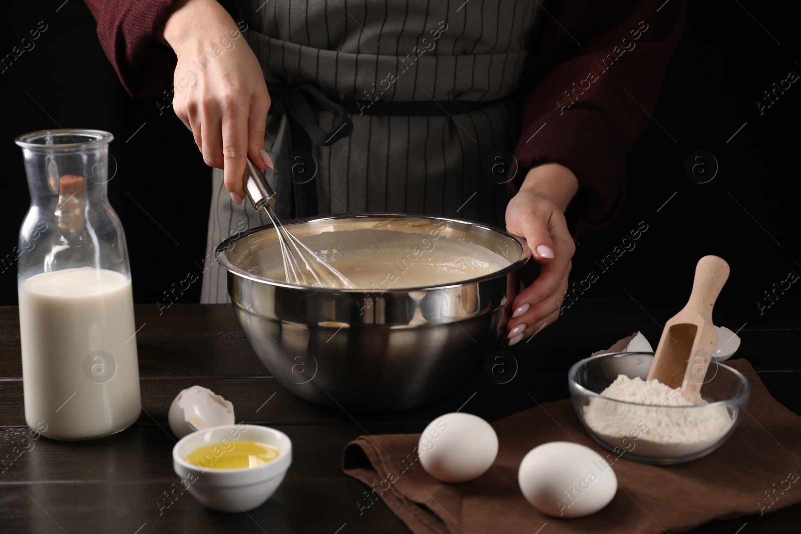 Photo of Woman making dough with whisk in bowl at table, closeup