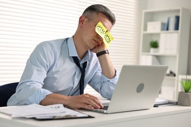 Photo of Man with fake eyes painted on sticky notes snoozing at workplace in office