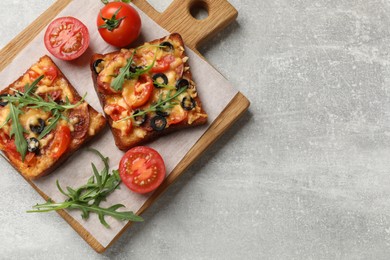 Tasty pizza toasts, fresh tomatoes and parsley on grey table, top view. Space for text