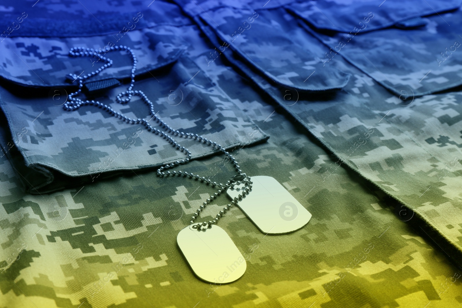 Image of Military ID tags with chain on camouflage uniform, toned in colors of Ukrainian flag