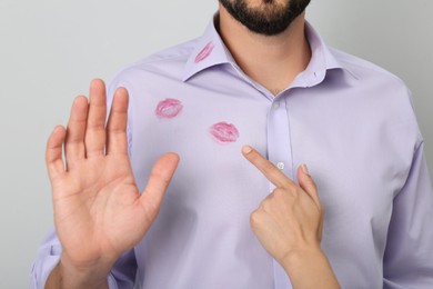 Photo of Woman pointing at lipstick kiss mark on her husband's shirt, closeup