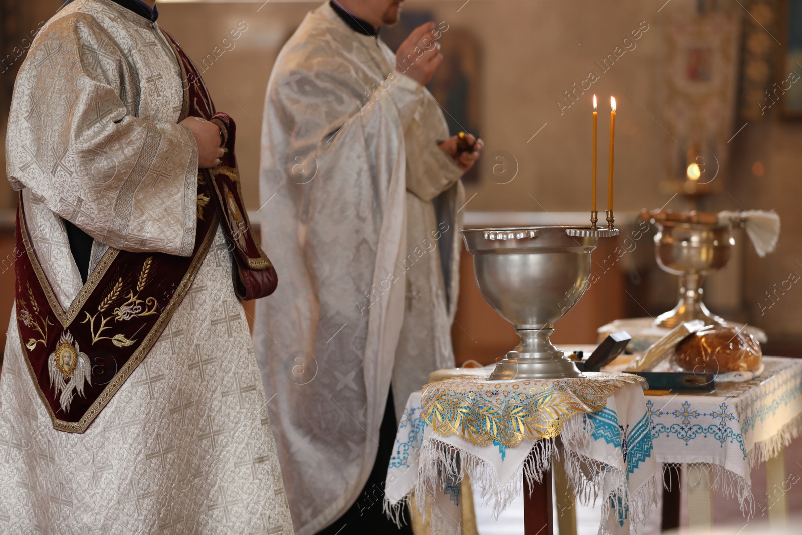 Photo of MYKOLAIV, UKRAINE - FEBRUARY 27, 2021: Deacon and priest conducting baptism ceremony in Kasperovskaya icon of Mother of God cathedral, closeup