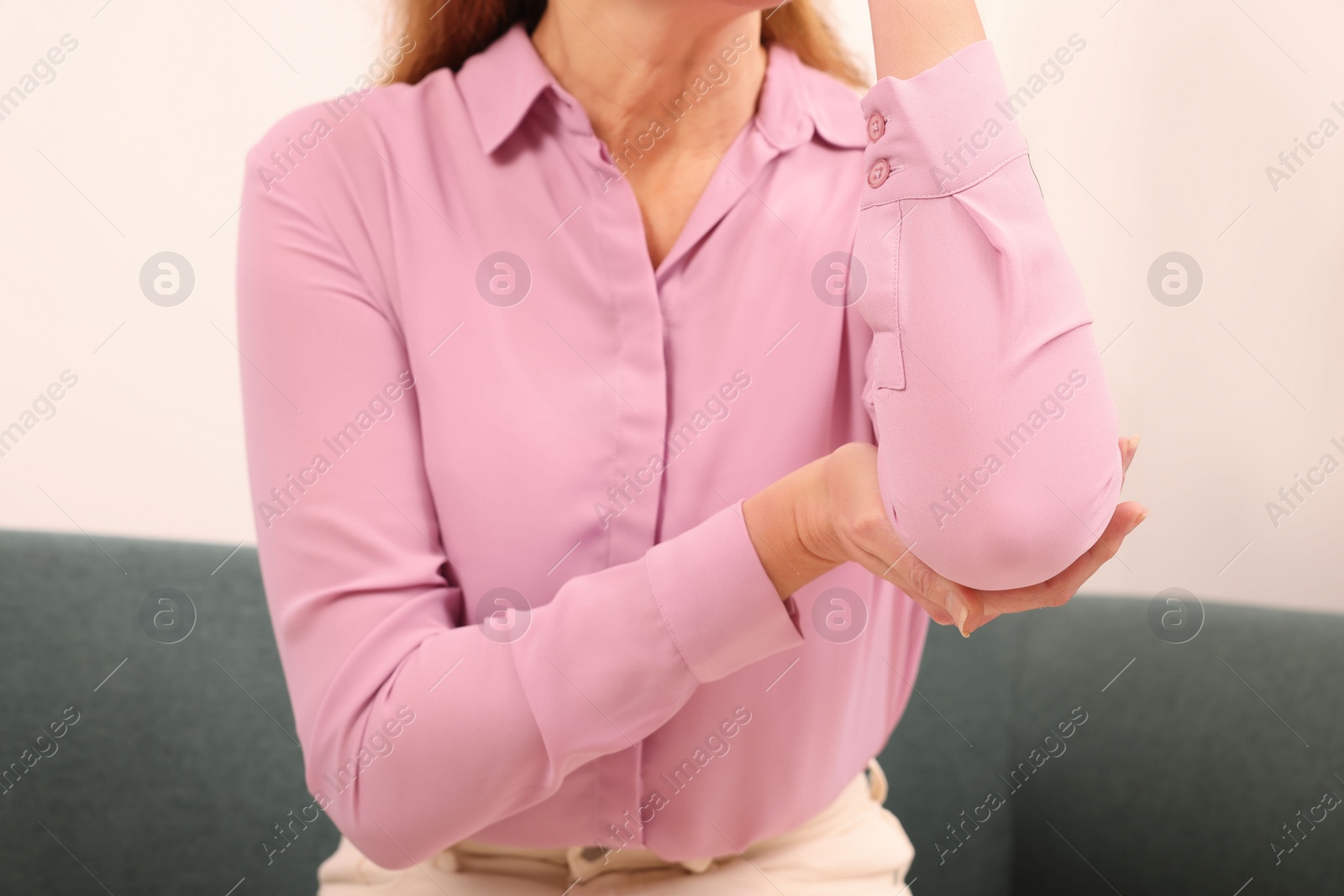 Photo of Woman suffering from pain in elbow indoors, closeup. Arthritis symptoms