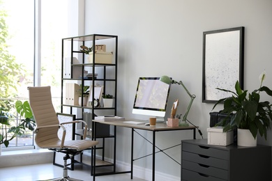 Photo of Comfortable office chair near desk with modern computer indoors