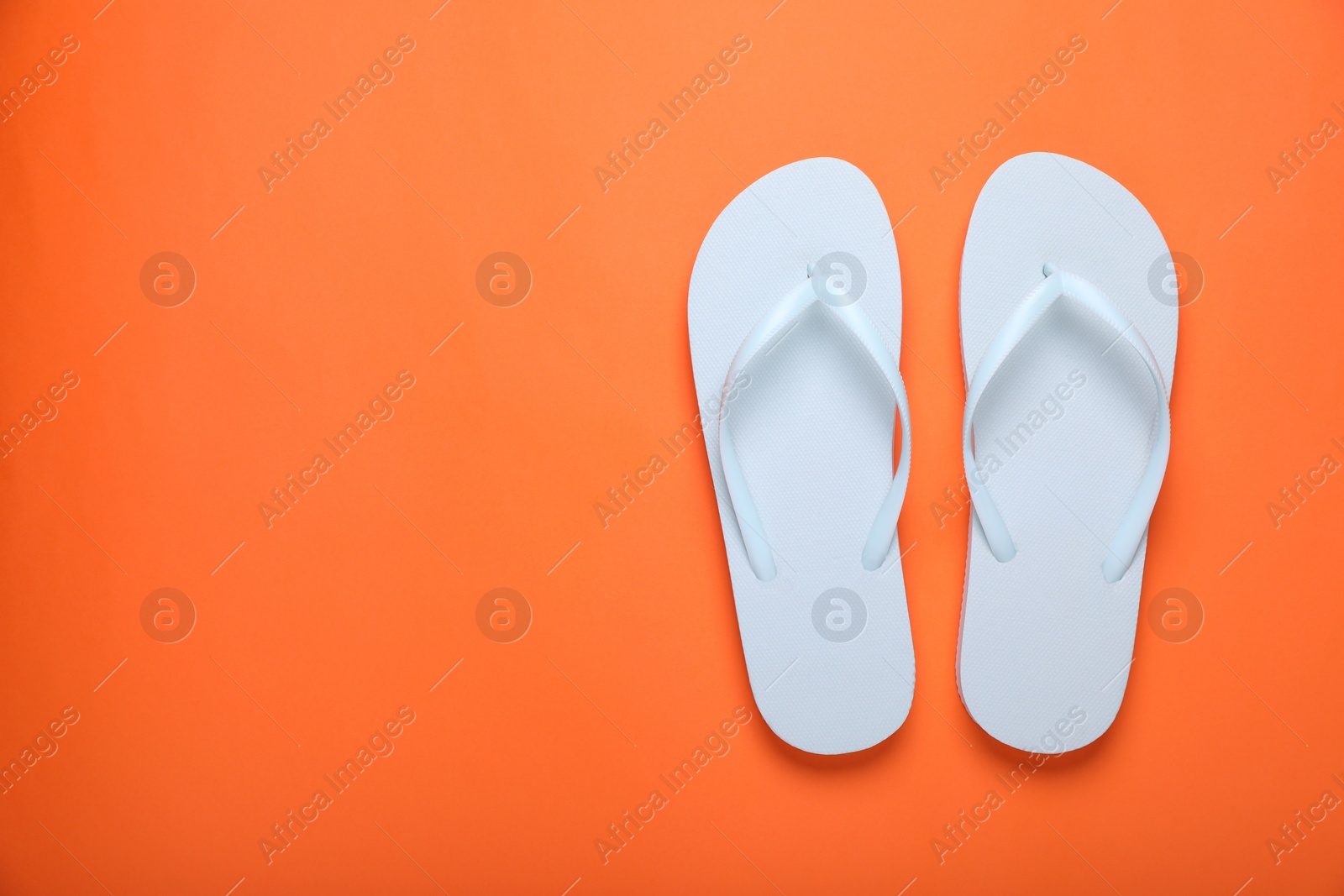 Photo of Stylish white flip flops on orange background, top view. Space for text