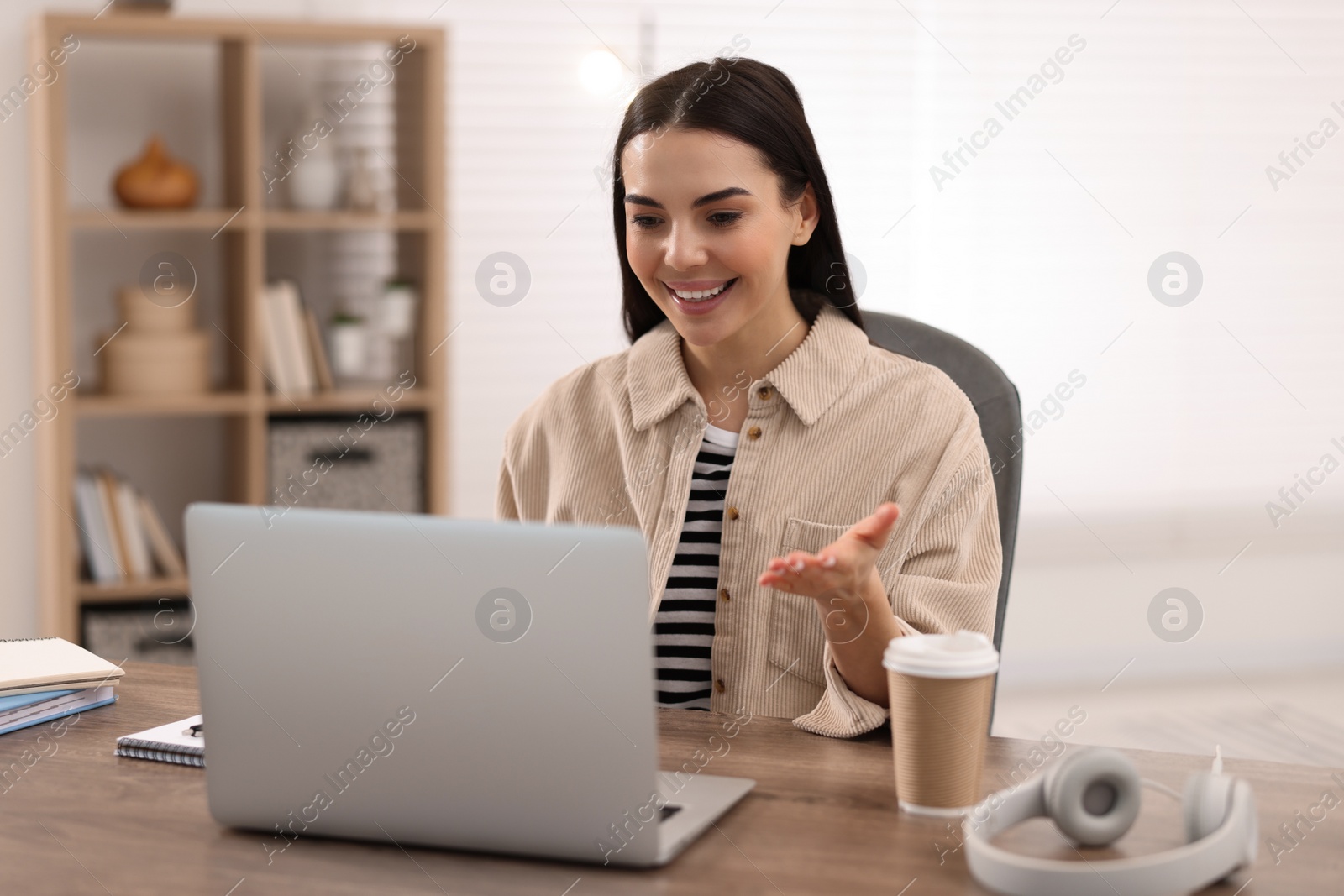 Photo of Young woman using video chat during webinar at table in room