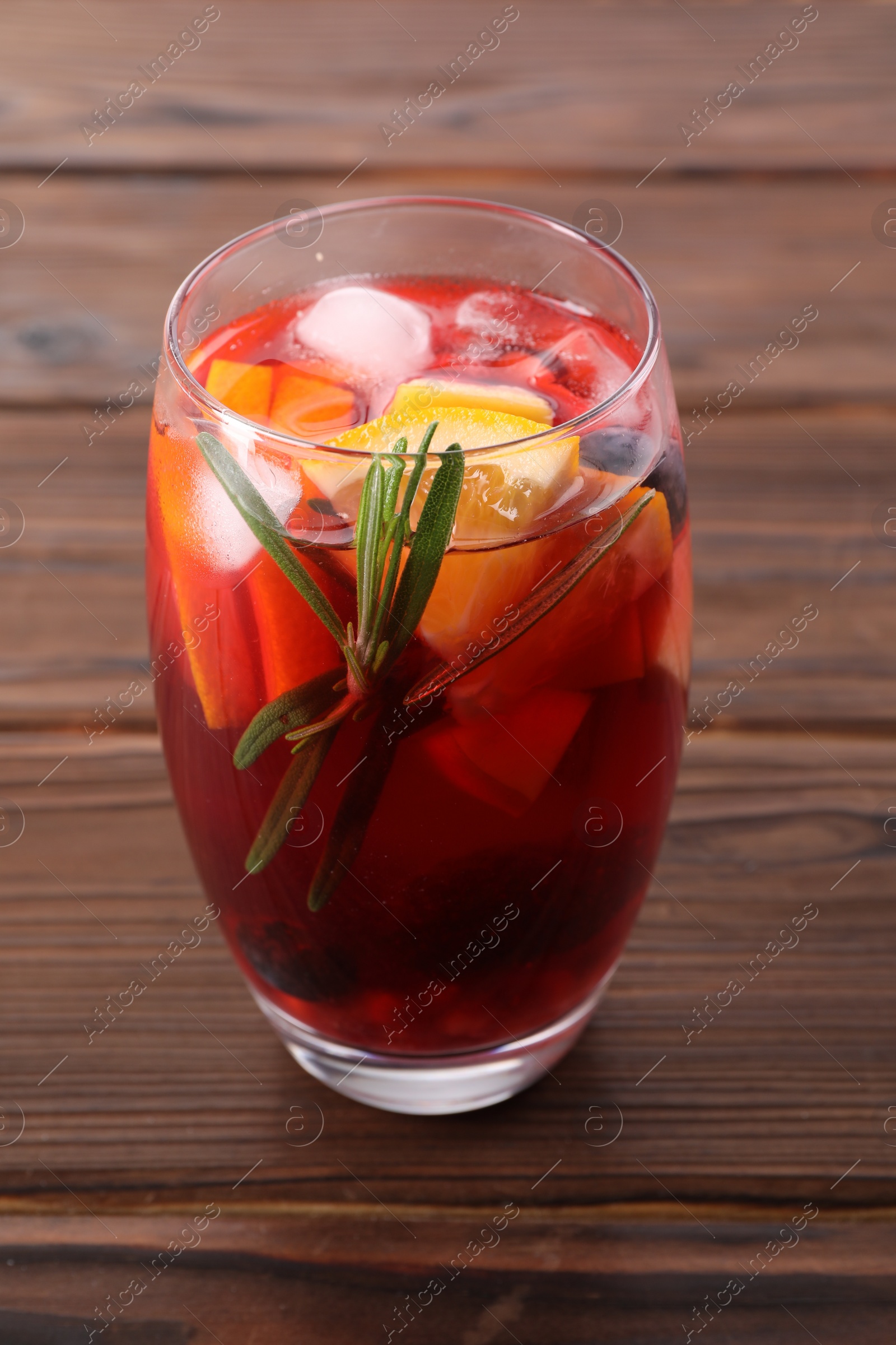 Photo of Glass of delicious sangria on wooden table, closeup