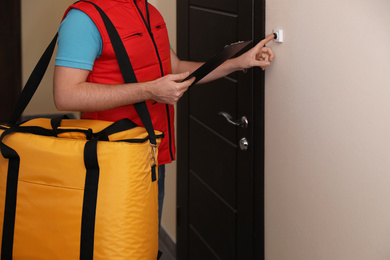 Male courier with thermo bag and clipboard ringing doorbell, closeup. Food delivery service