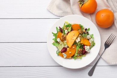 Delicious persimmon salad and fork on white wooden table, flat lay. Space for text