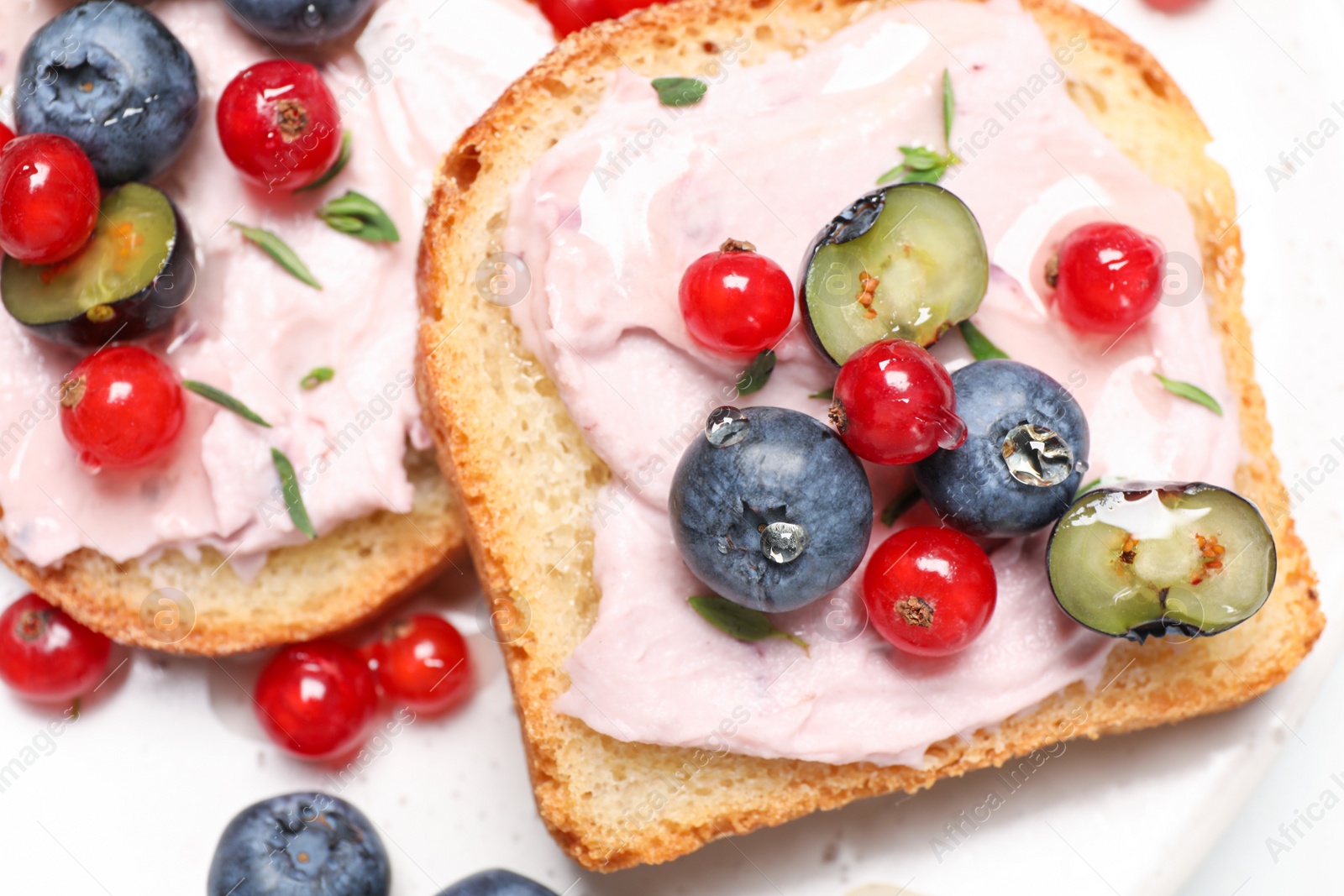 Photo of Tasty sandwiches with cream cheese, blueberries and red currants, closeup