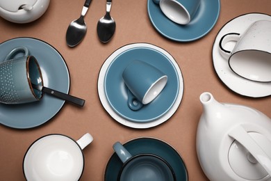 Photo of Different cups and teapot on brown background, flat lay