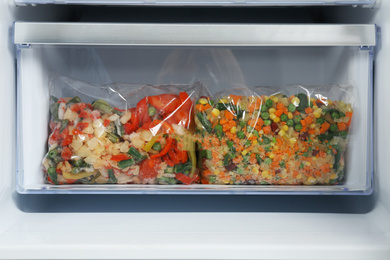 Bags with frozen vegetables in modern refrigerator