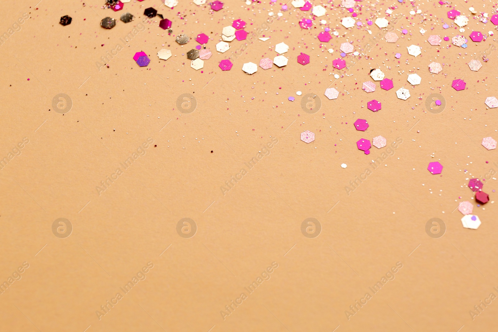 Photo of Shiny bright pink glitter on beige background. Space for text