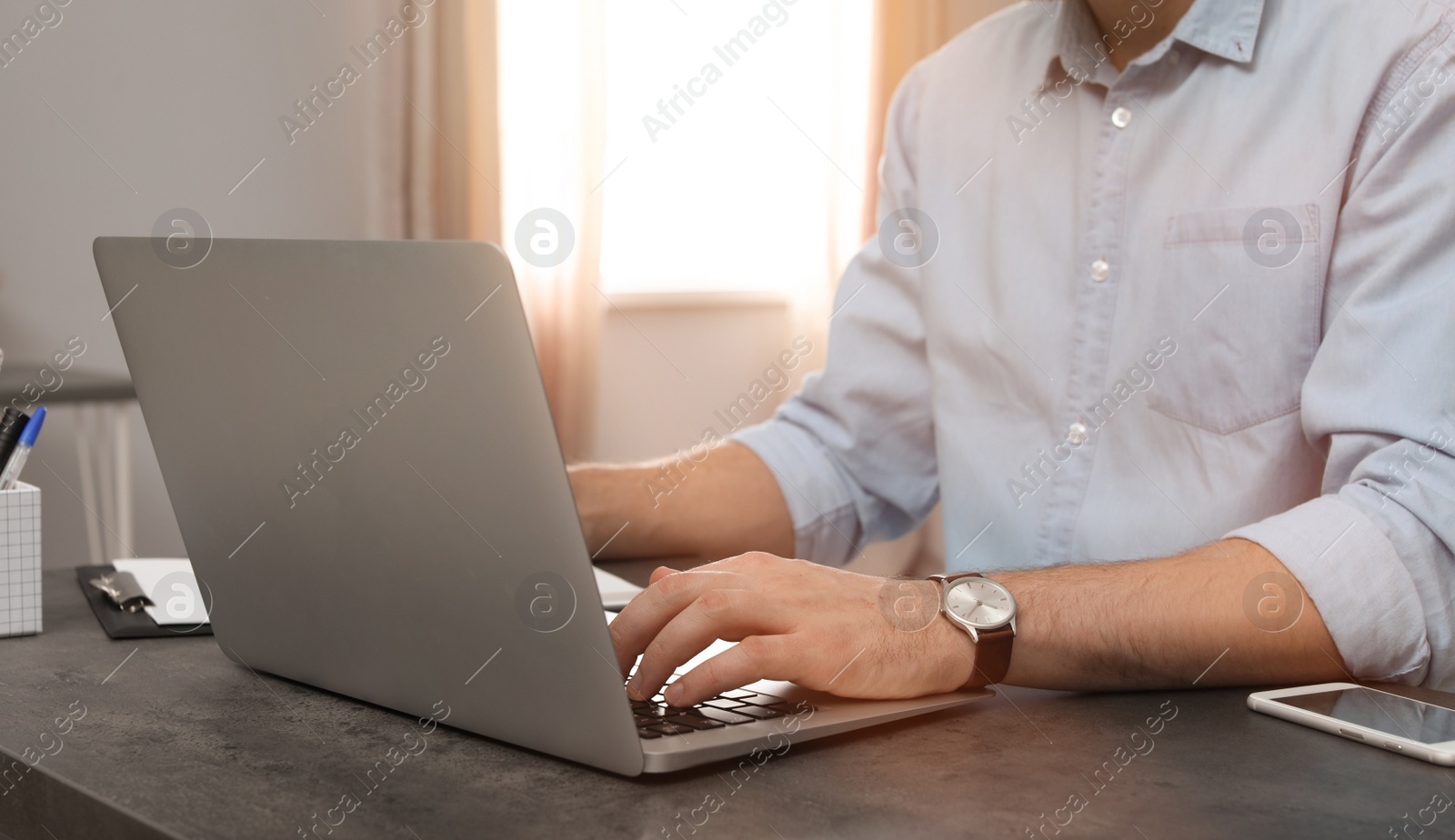 Photo of Young man working with laptop at desk in home office