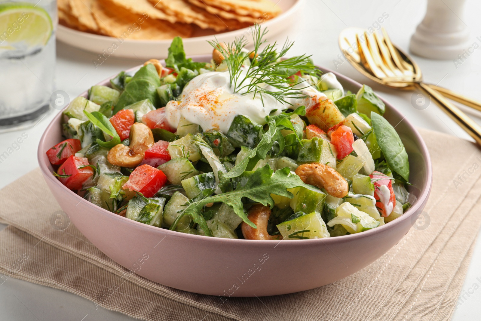 Photo of Bowl of delicious cucumber salad served on white table, closeup