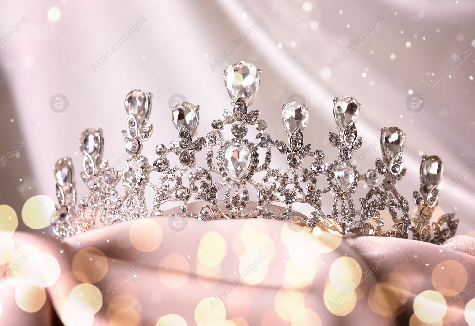 Image of Beautiful tiara with diamonds on pink cloth, bokeh effect