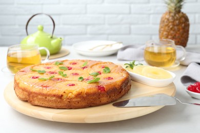Photo of Tasty pineapple cake with cherries and mint on white table