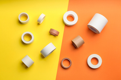 Photo of Sticking plaster rolls on color background, flat lay