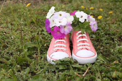Photo of Shoes with beautiful flowers on grass outdoors