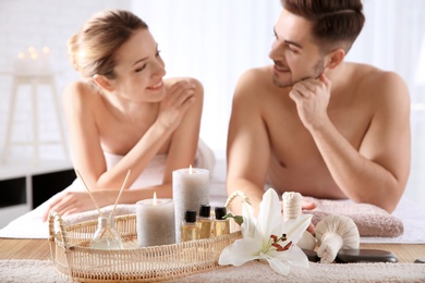 Photo of Young couple with spa essentials in wellness center